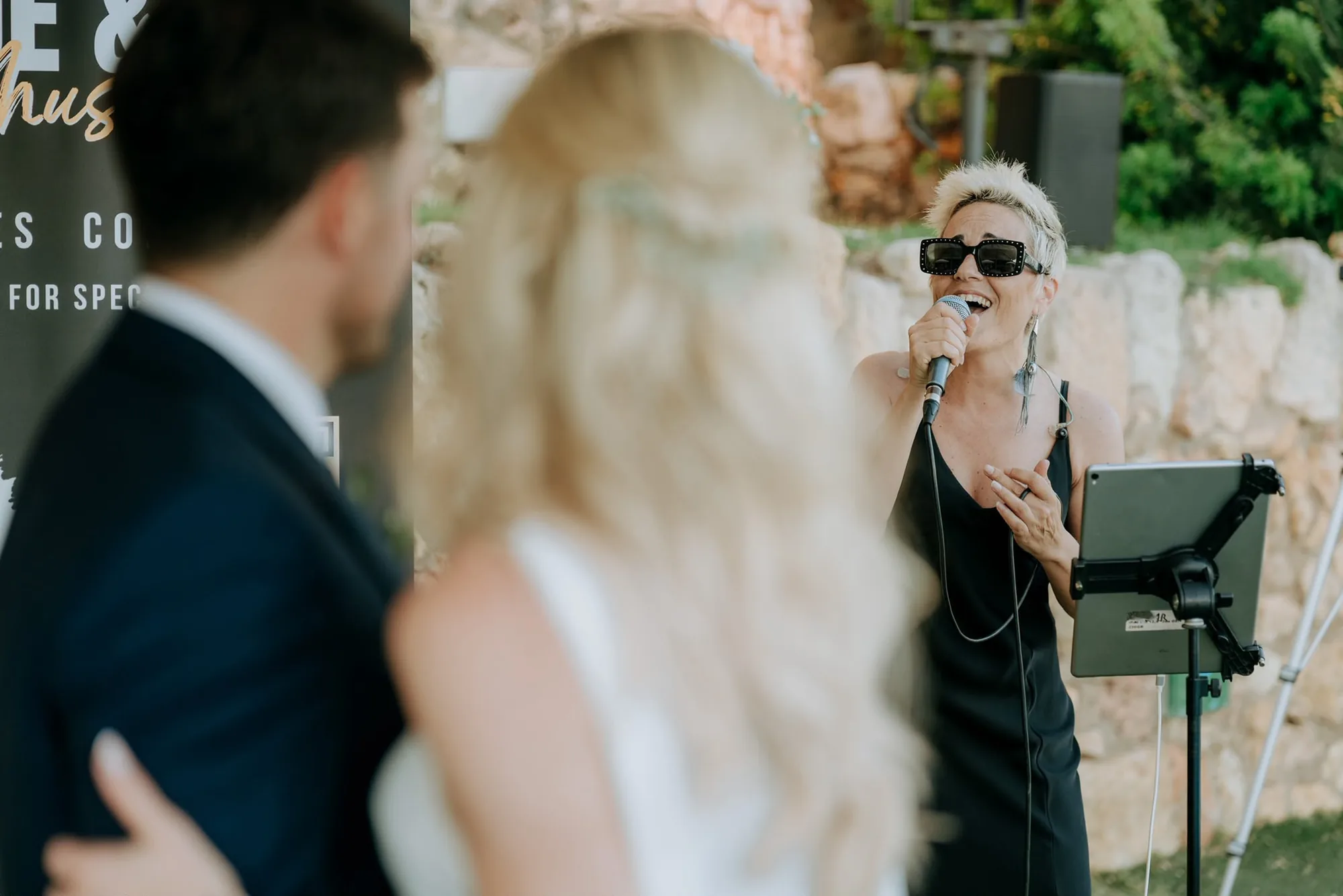 Chloe Ly cantando en una ceremonia al aire libre mientras los novios la escuchan